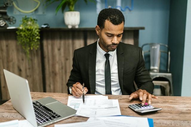 A man in a black suit, working.