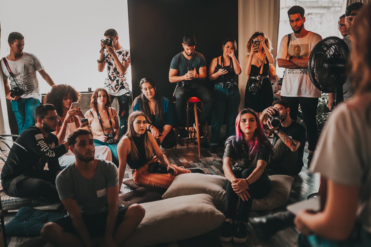 A diverse group of people sitting on the floor, engaged in conversation in a cozy room setting.