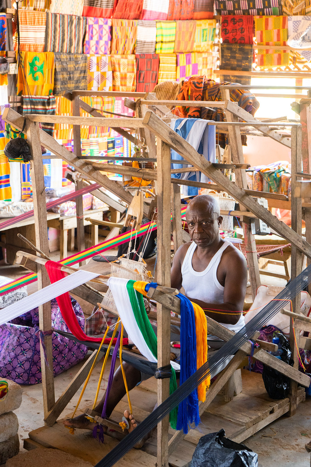 a man weaving bonwire kente with skill and dexterity