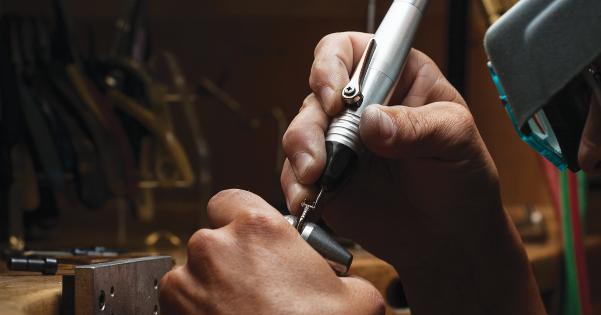 A jeweler using a jewelry drill to fix a gold and diamond ring