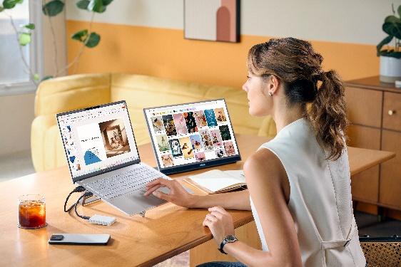 A person sitting at a desk with two laptops

Description automatically generated