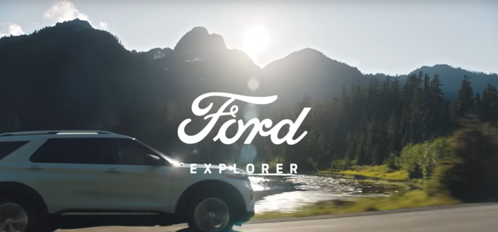 A Ford Explorer and accompanying logo in front of an expanse of mountains