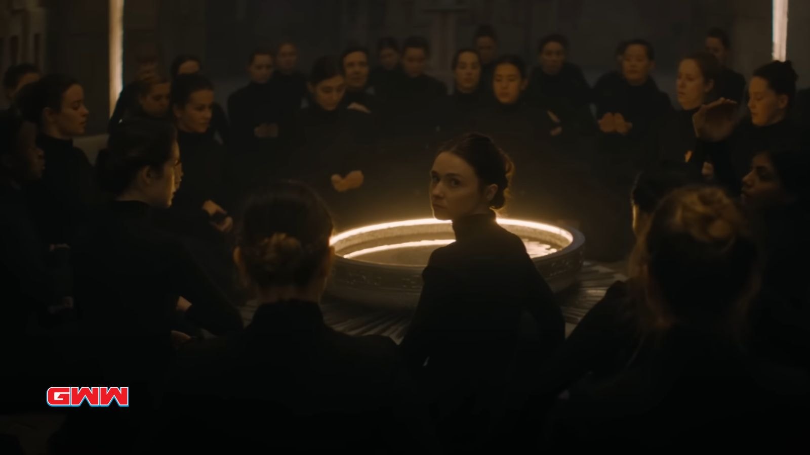 Group of Bene Gesserit in black robes, sitting in a circle, dimly lit room.