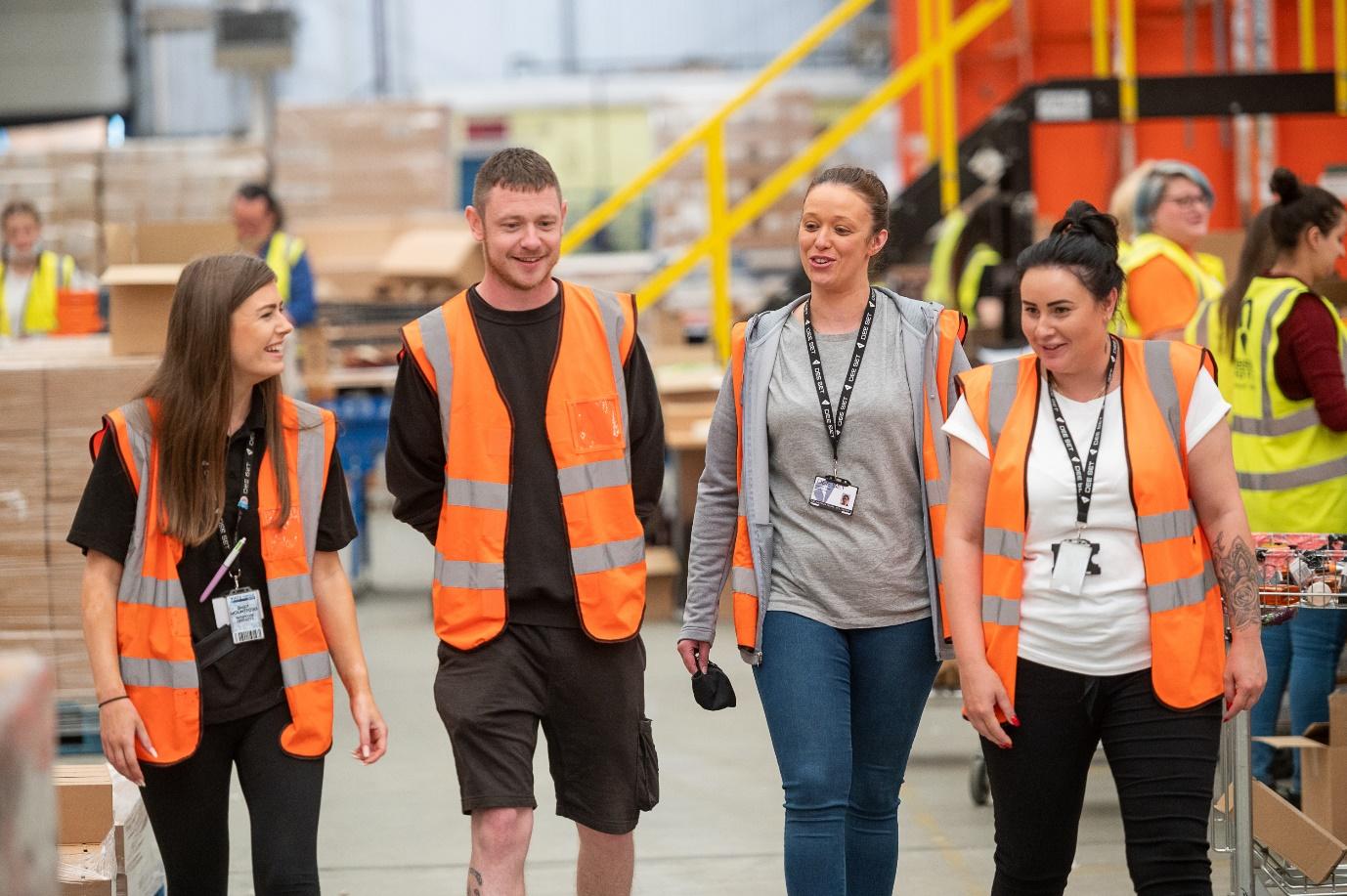 A group of people wearing orange vests walking

Description automatically generated