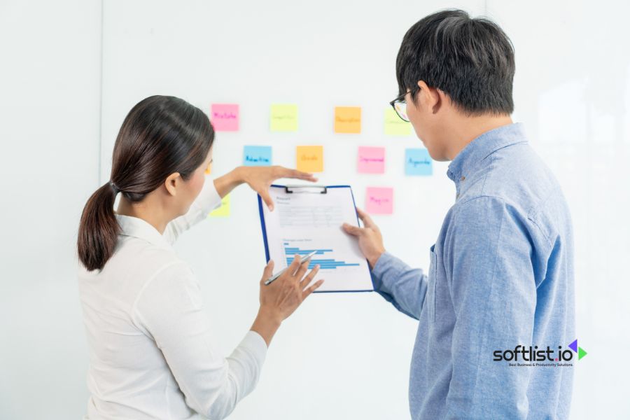 Two colleagues discussing a project with sticky notes on the wall.