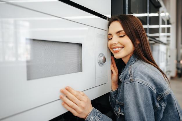 Young woman selected a new microwave oven in hypermarket