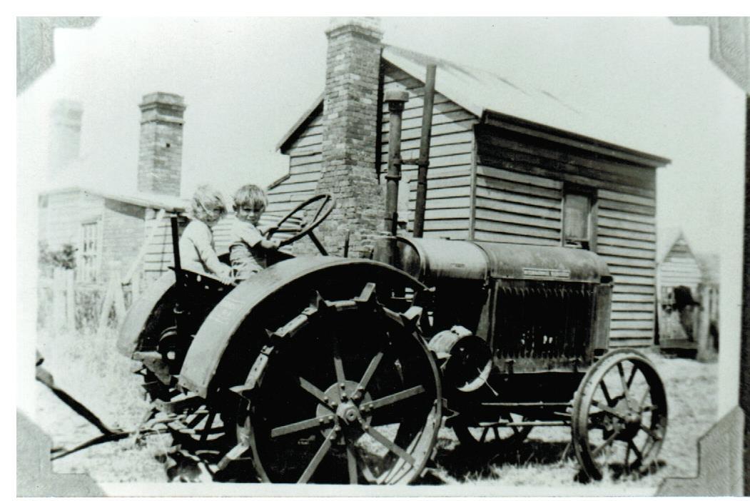 A couple of children sitting on a tractor

Description automatically generated