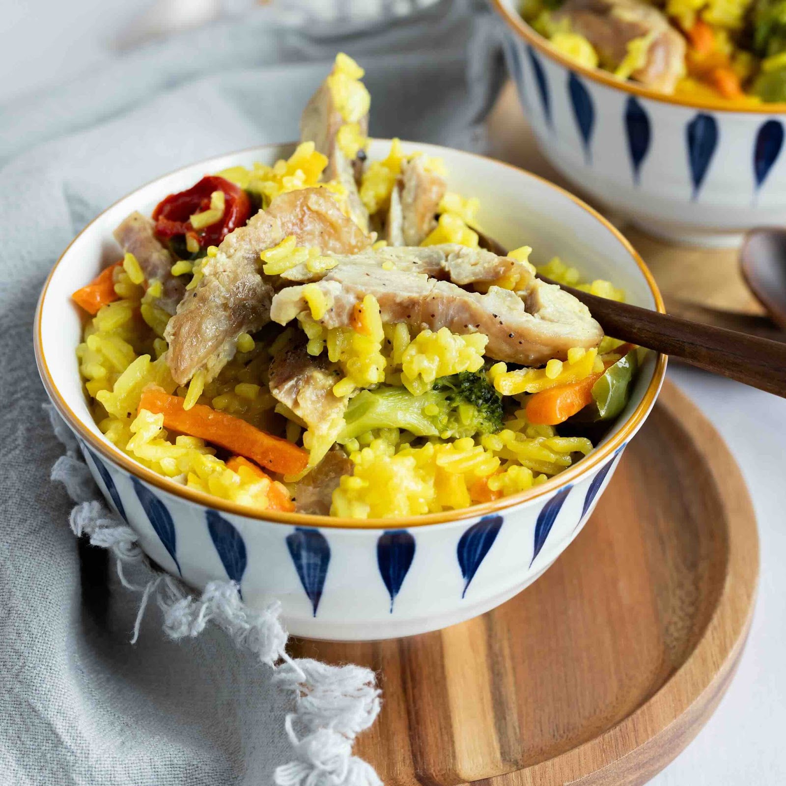 Sauté de poulet avec du riz jaune et des légumes dans un bol en céramique.