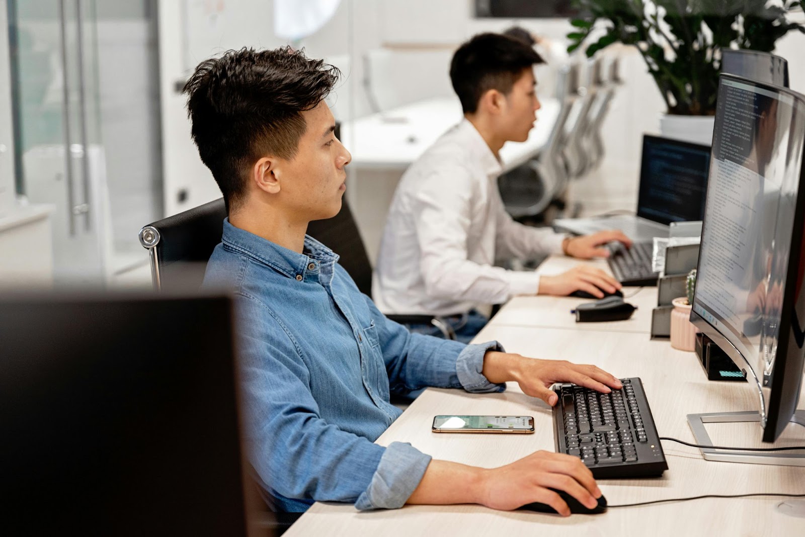  Two office workers sit at a table with their computers.