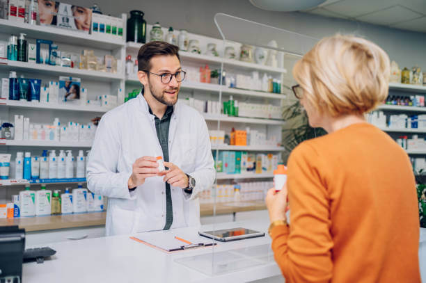 A friendly pharmacist in a white coat talking to a customer at Thornhill’s Pharmacy, holding a bottle of curcumin phytosome supplements and explaining its benefits.