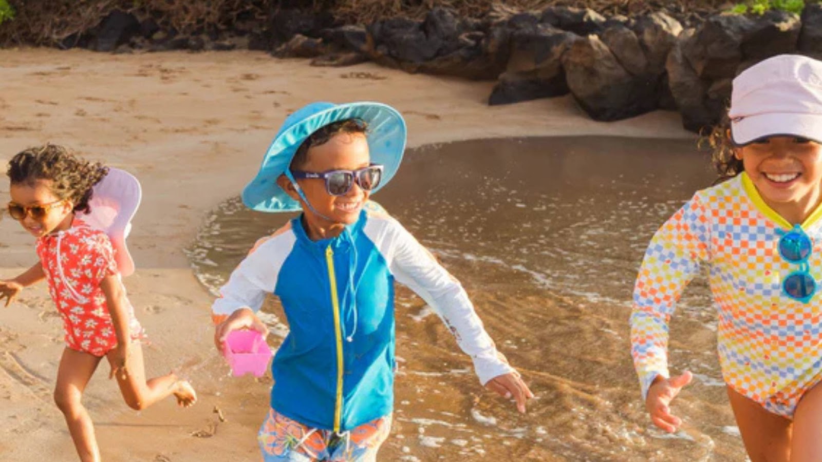 Kids with SwimZip sunglasses and sun hats at the beach—Sunburn safety: All you need to know to stay safe in the sun