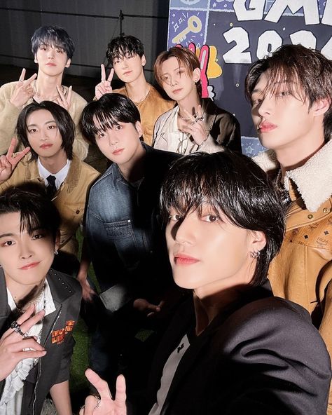 This contain ATEEZ  are posing together for a photo in front of a poster