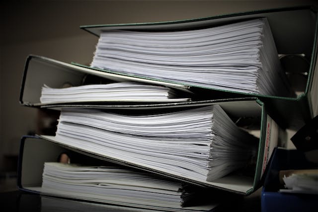 A stack of several large binders full of paper