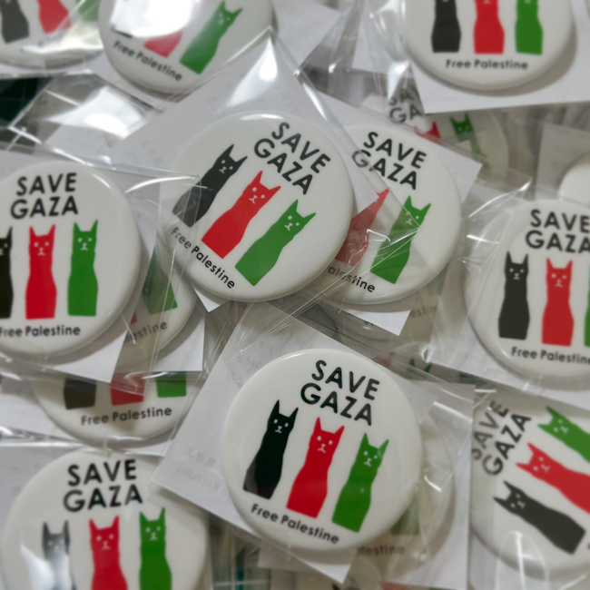 白い背景の丸いバッジ。
上部に「Save Gaza」という文字が黒で書いてあり、
その下の３匹の猫（左から黒、赤、緑）が正面を向いて並んで座っている絵が描かれている。