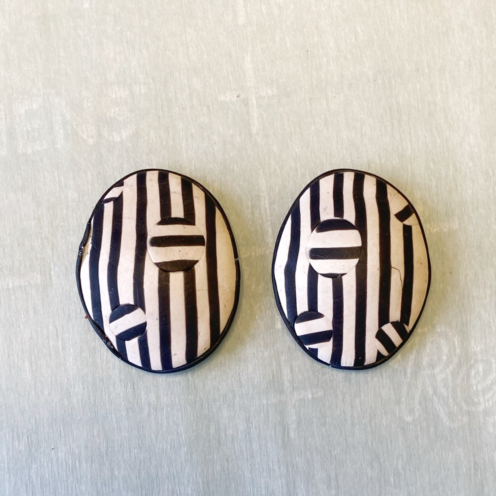 Black and white polymer clay earrings after baking, front view.