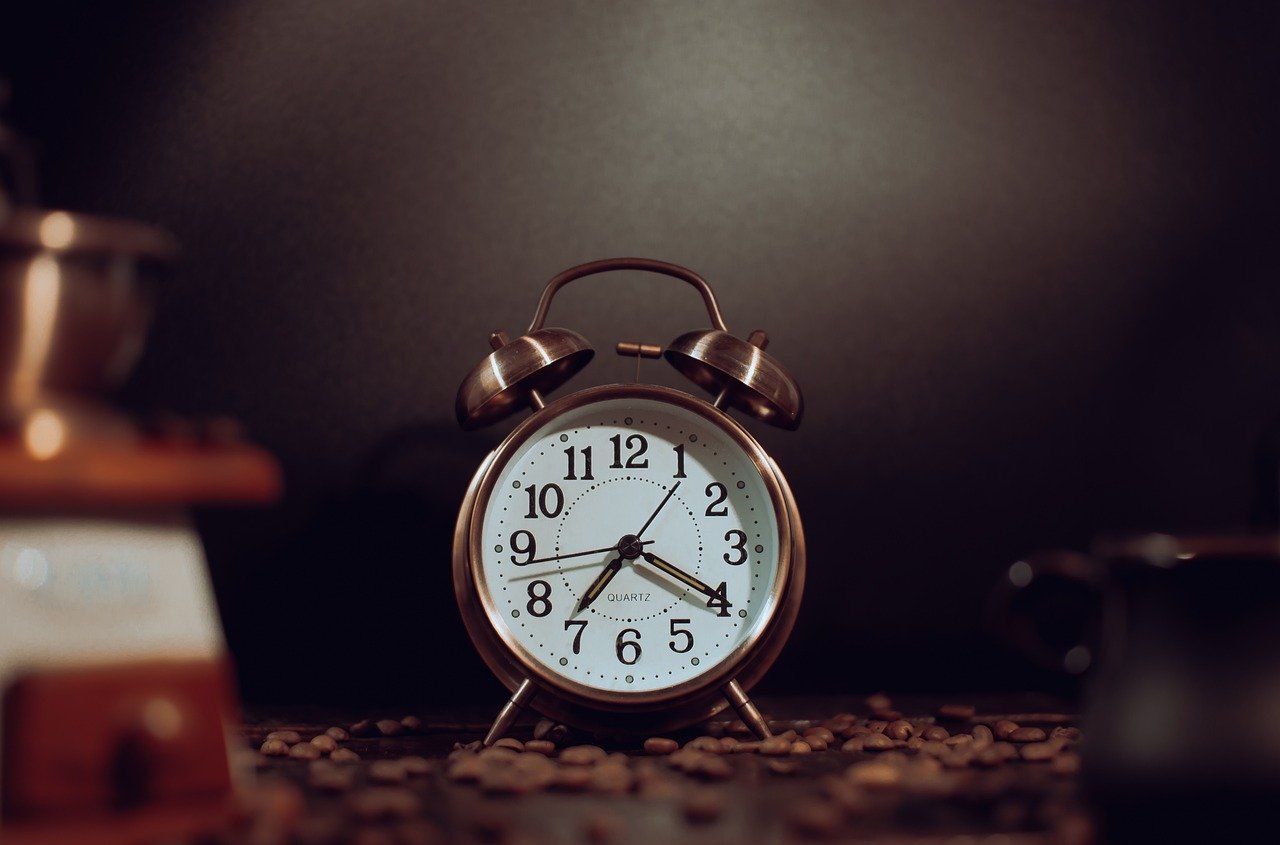 Vintage alarm clock on a surface scattered with coffee beans