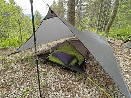 An imaging displaying a tent set up on an elevated ground in the forest as a top survival hack for rainy weather camping