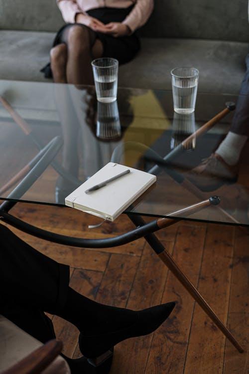 Free White and Silver Chair Beside Clear Drinking Glass on Glass Table Stock Photo