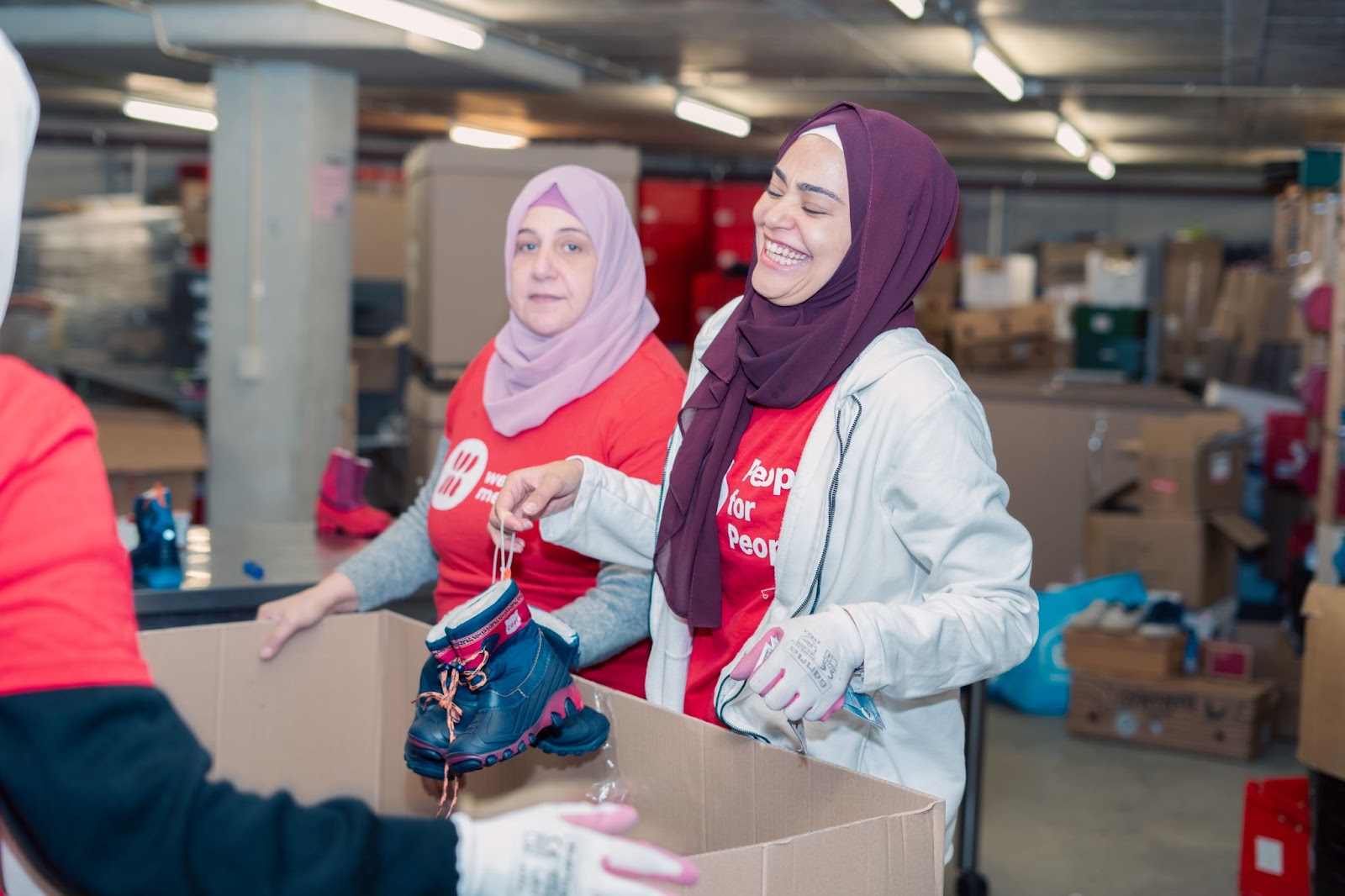 Walaa and her mother sorting clothes in the People for People warhouse.