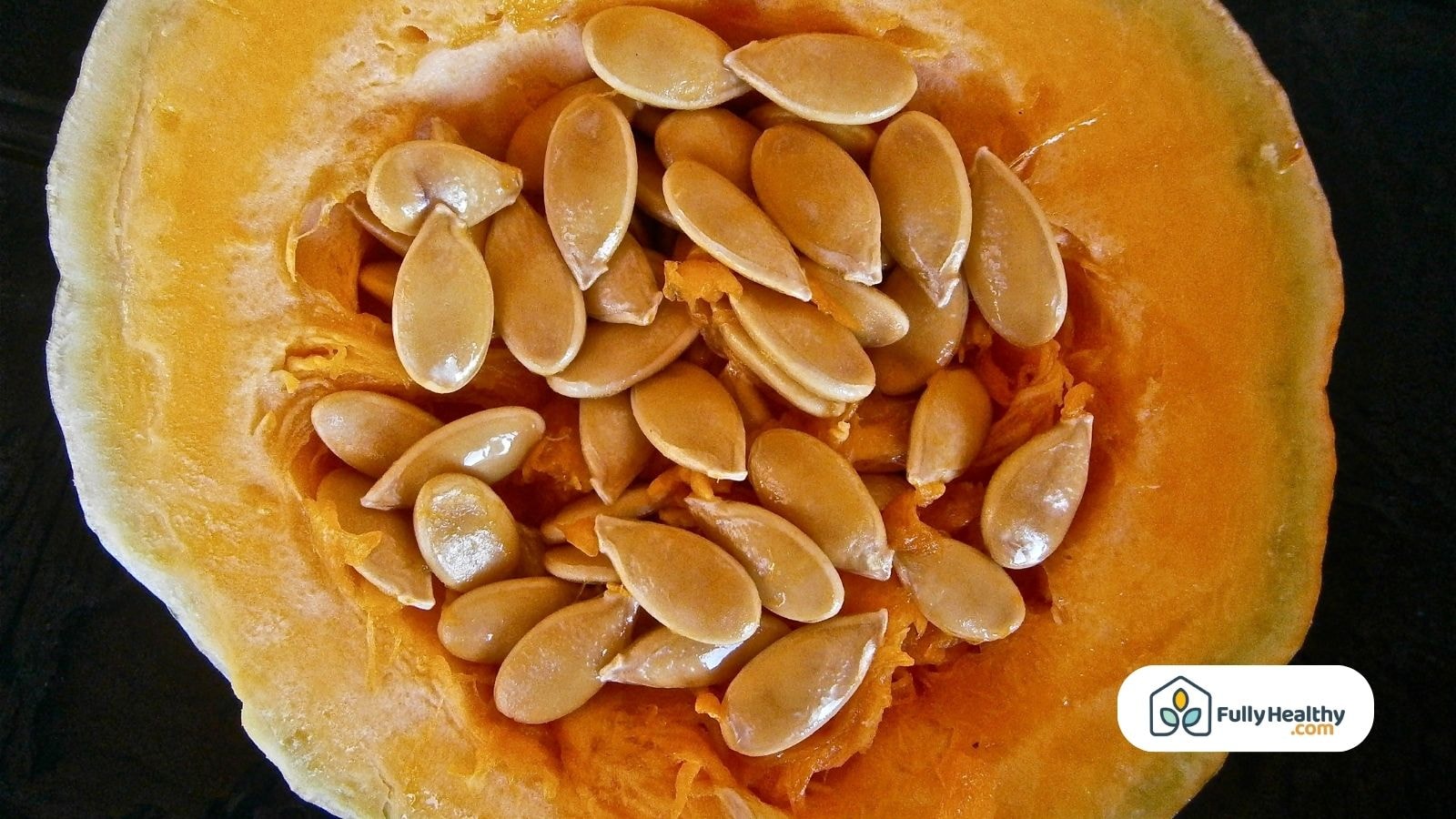 Close-up of raw pumpkin seeds inside halved pumpkin.