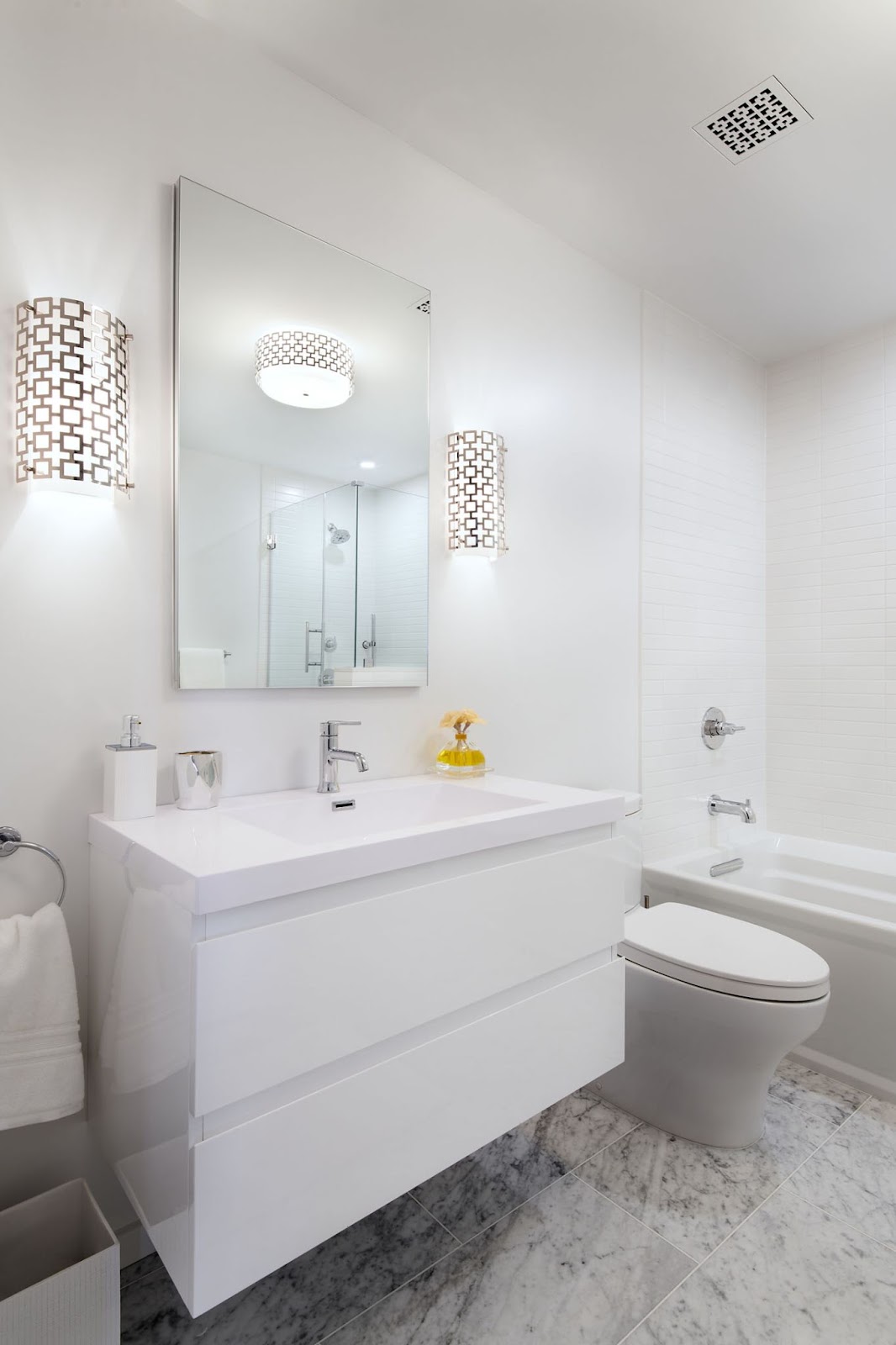 Full bath with white floating vanity, marbled floor tile, tub-shower combo with subway tile, and chrome fixtures