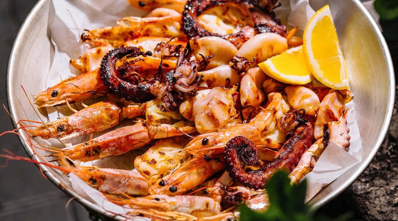 Grilled seafood platter featuring shrimp, octopus, and squid, served with fresh lemon wedges. This protein-rich and healthy Mediterranean dish is a delicious option for seafood lovers in Mississauga, recommended by our registered dietitian for a nutritious meal.