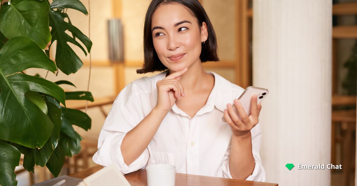 A woman holding a phone and smiling | Emerald Chat