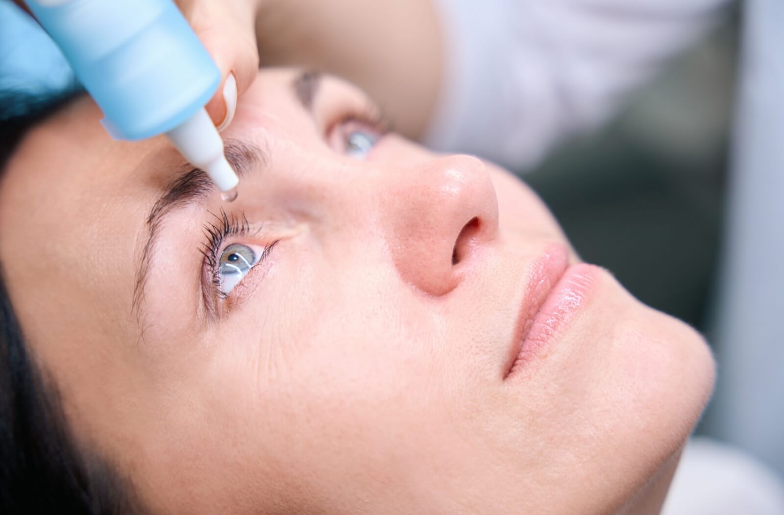 A female patient receiving eye drops for her dilated retinal exam.