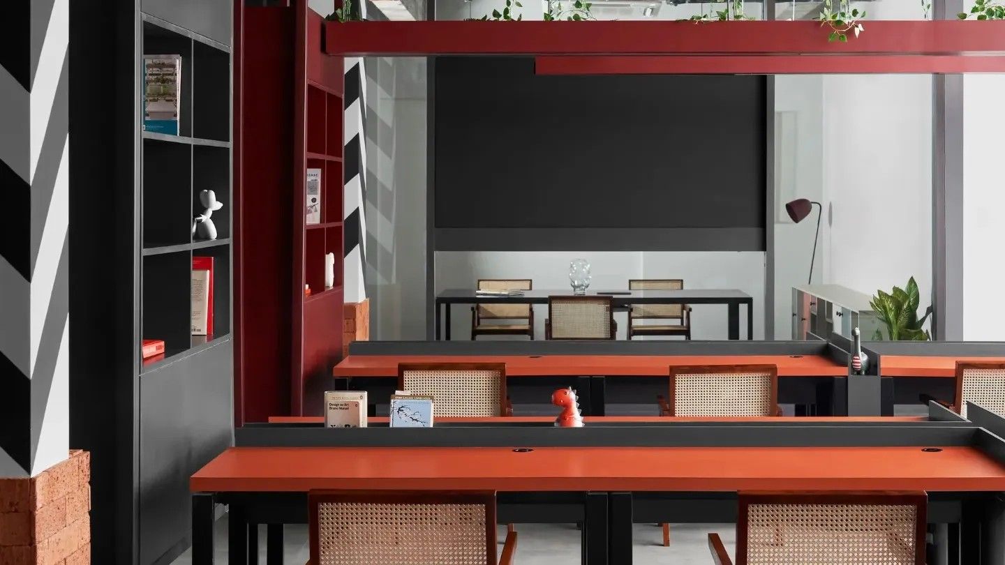 A modern, minimalist office space featuring black and orange desks with woven-back chairs blends innovative office designs with productive environments.