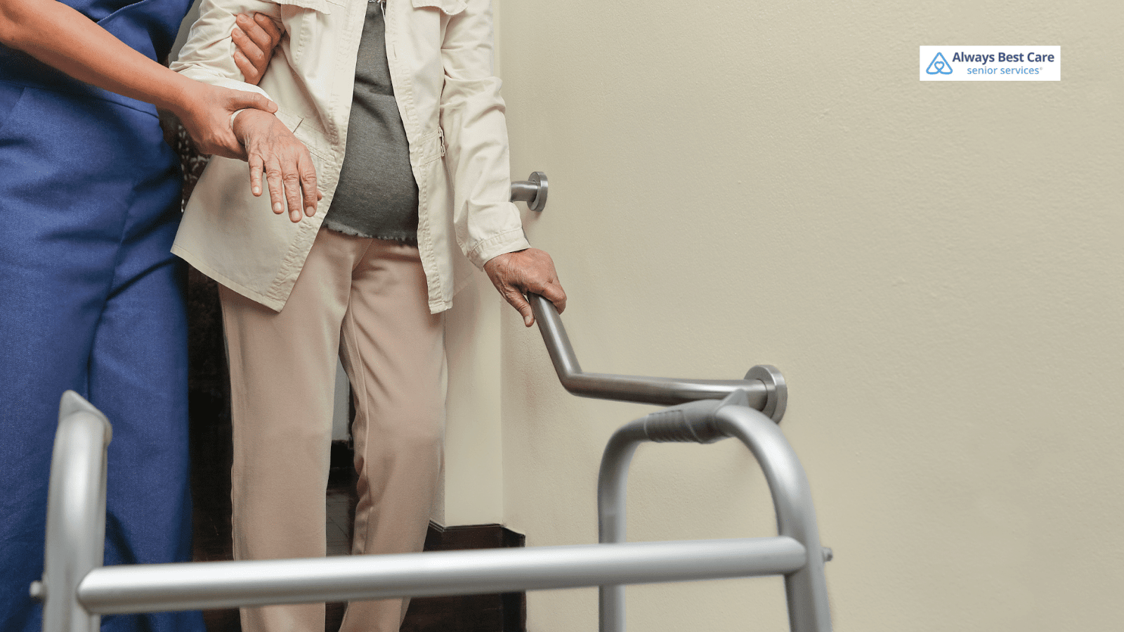 This image depicts a caregiver helping a senior walk down the stairs while holding a grab bar