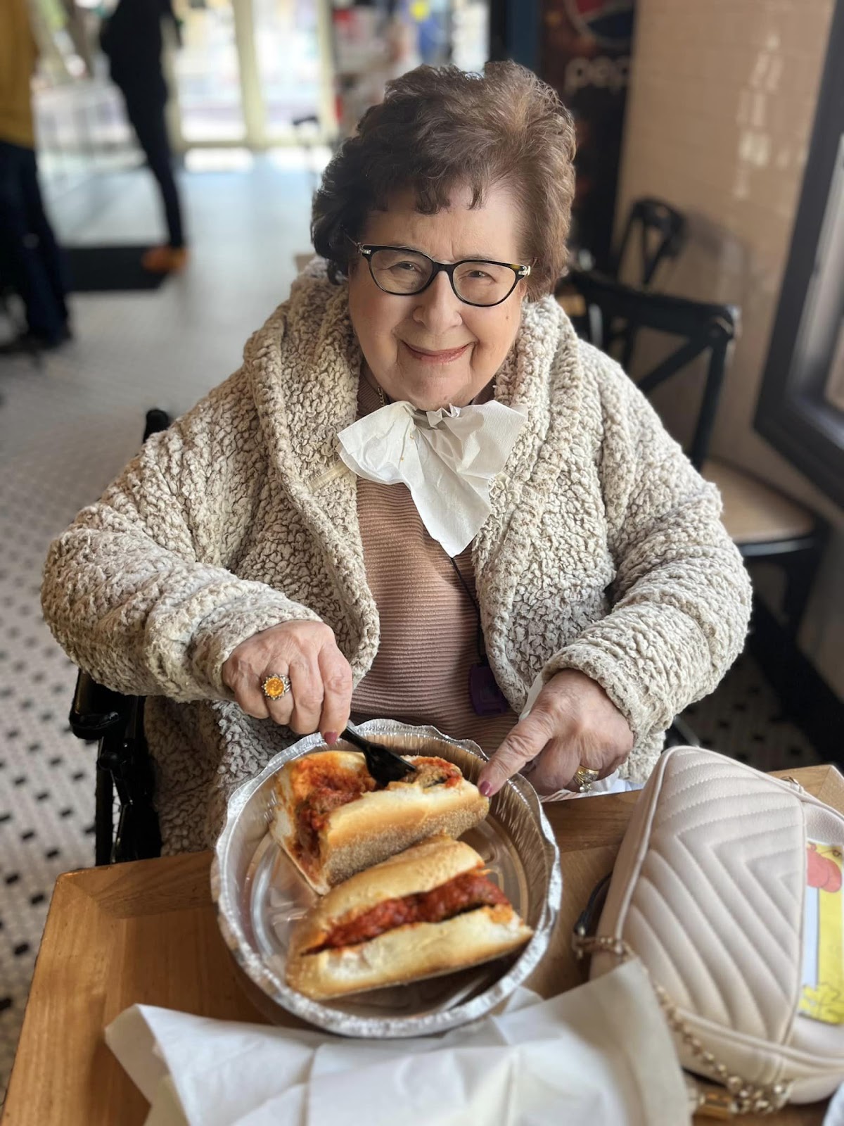 An assisted living resident eating a sandwich in a restaurant with a fork and knife