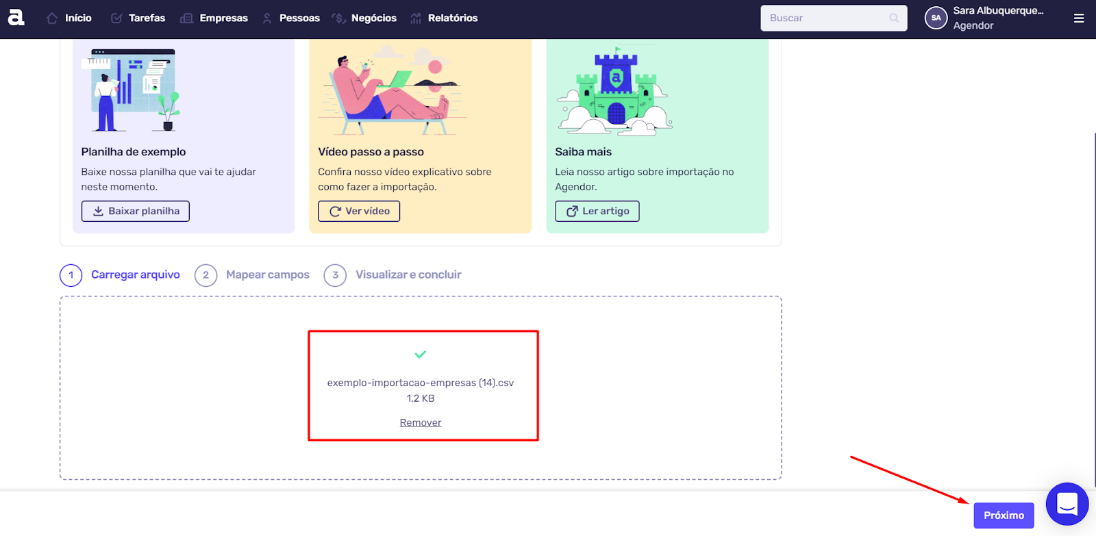 Tela de importação do Agendor, mostrando o arquivo 'exemplo-importacao-empresas.csv' carregado e destacado por um retângulo vermelho. Uma seta vermelha aponta para o botão 'Próximo' no canto inferior direito.