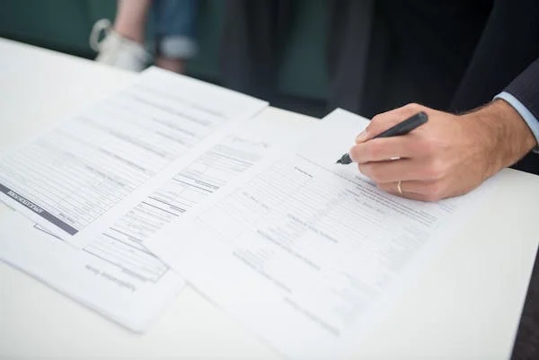 A person is filling an employment verification document with a pen in their hand