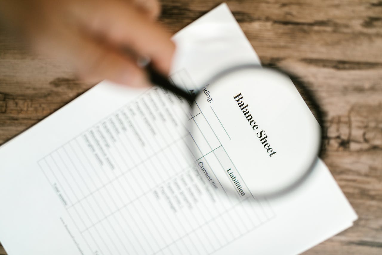 A business report with the word "Balance Sheet" displayed with a magnifying glass