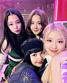 This contain BLACKPINK members  are posing together in front of a pink wall and purple lights, with their arms around each other