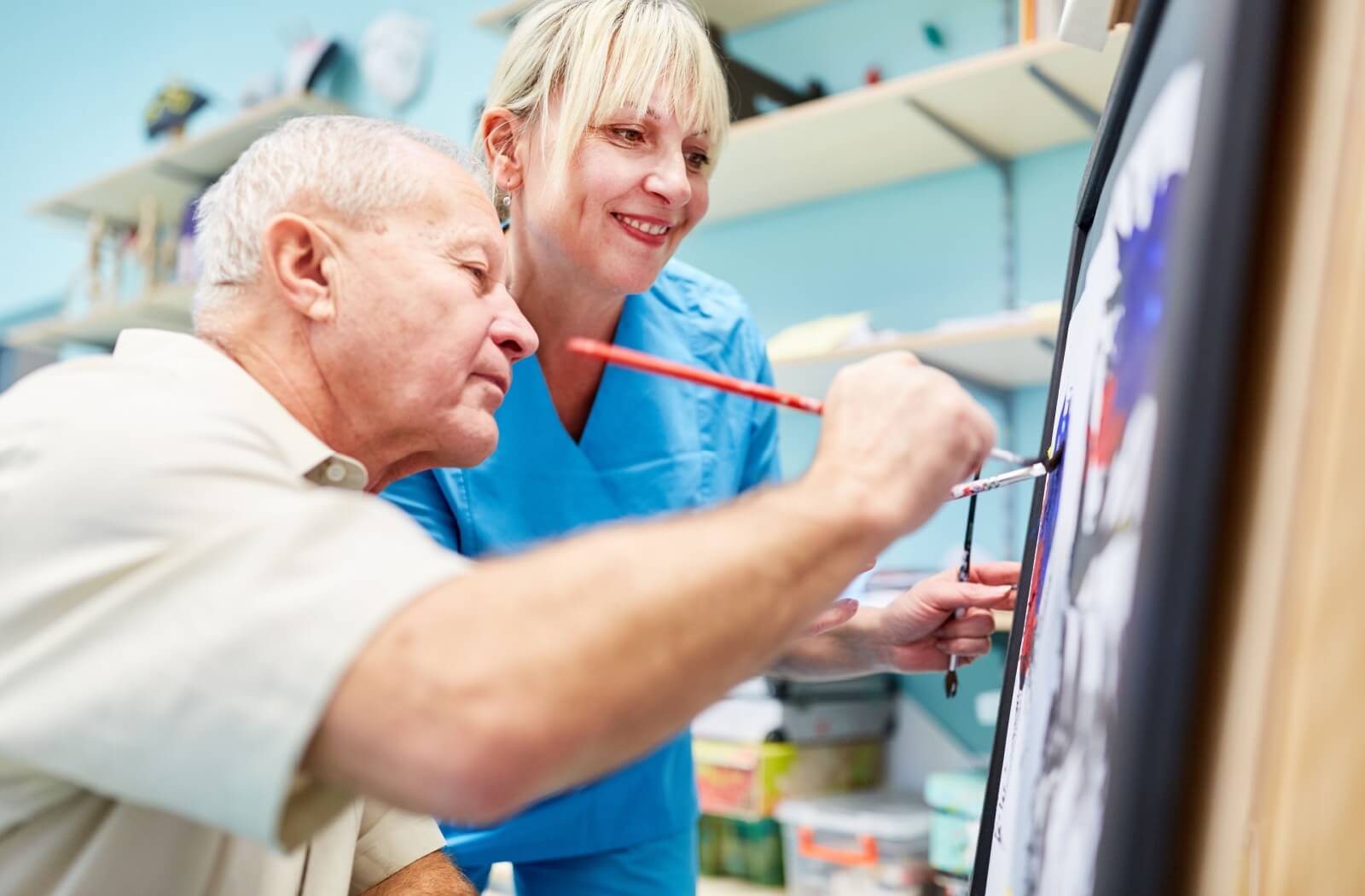 An older adult man painting on a canvas as a part of art therapy.