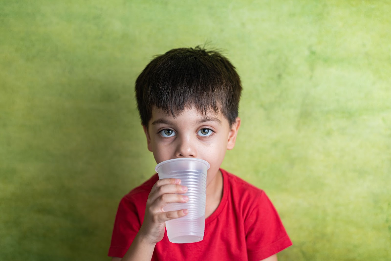 A little boy drinking a cup of water