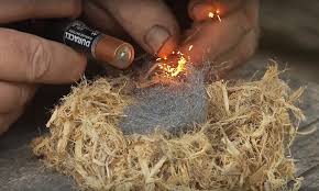 Someone using a battery and steel wool to light fire as a technique on  how to start a fire without matches or lighters