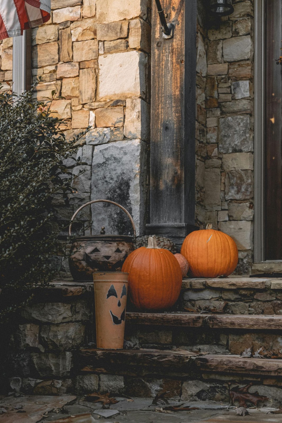 Natural stone front steps with pumpkins and two painted metal pales that look like pumpkins