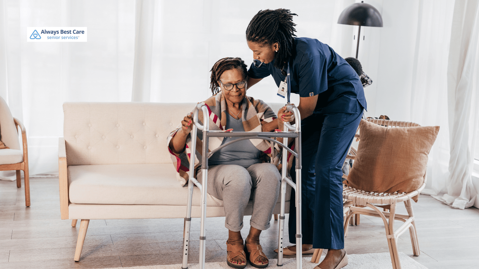 This image depicts a caregiver helping a senior woman stand up while using a walker