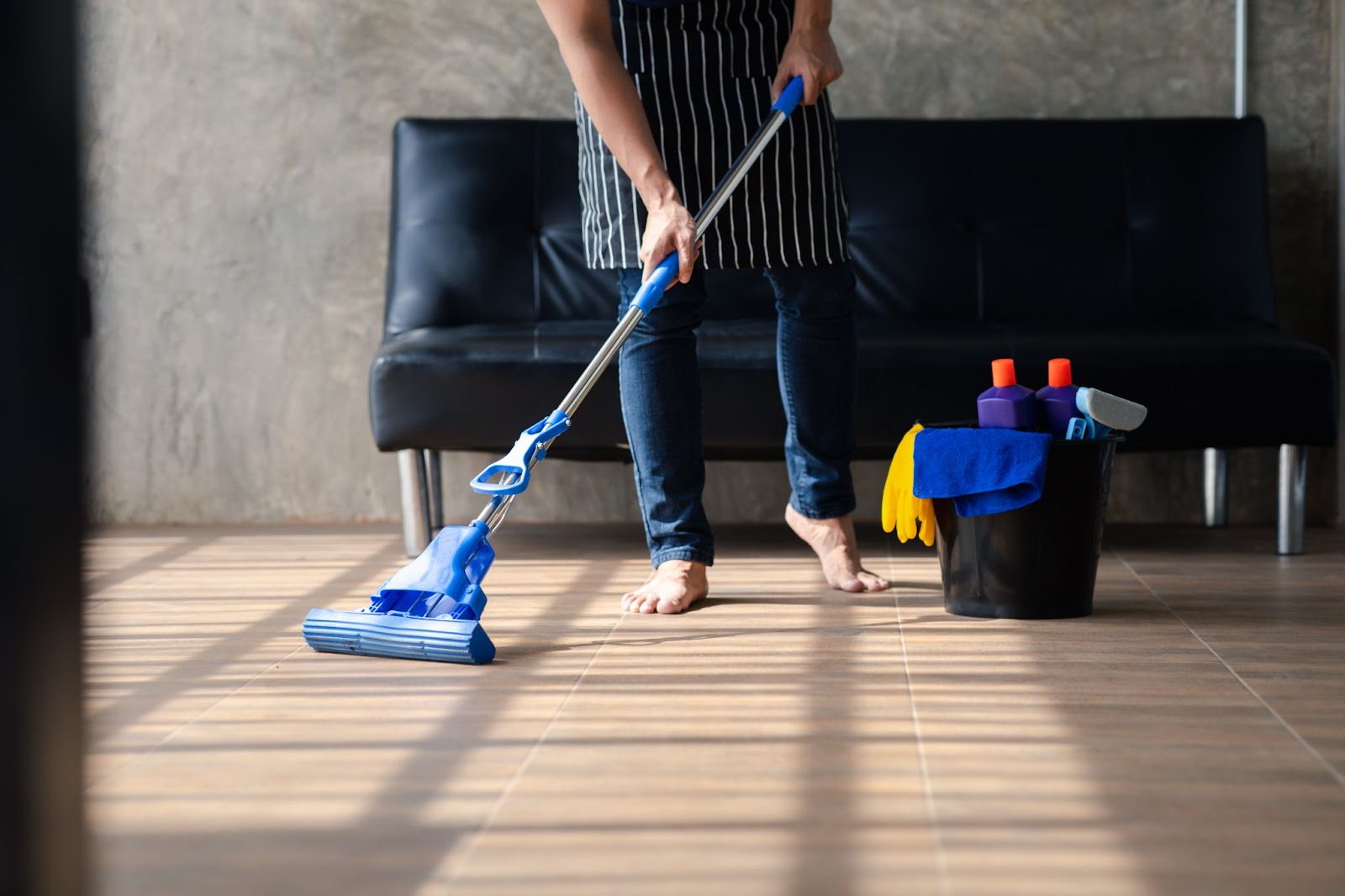 A man cleans his living room space with a mop and bucket.