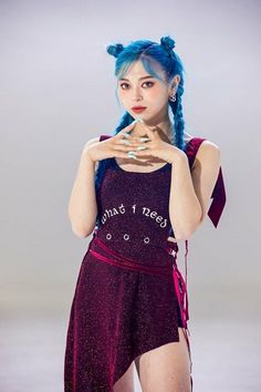 This contains an image of AleXa with a blue hair wearing a purple dress and holding her hands to her chest