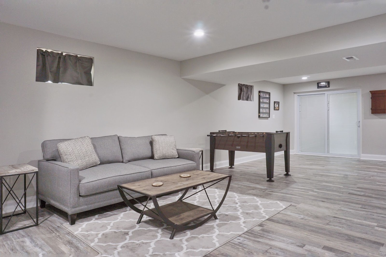 Basement with a couch, table, and foosball table. 