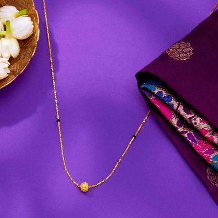 A gold necklace with a ball on it next to a bowl of flowers

AI-generated content may be incorrect.