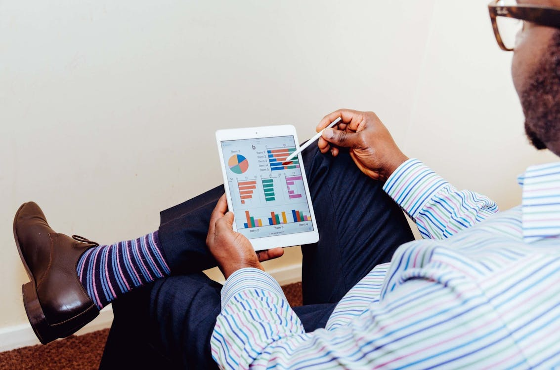Man analyzing social media performance statistics on an iPad, assessing engagement metrics and growth trends