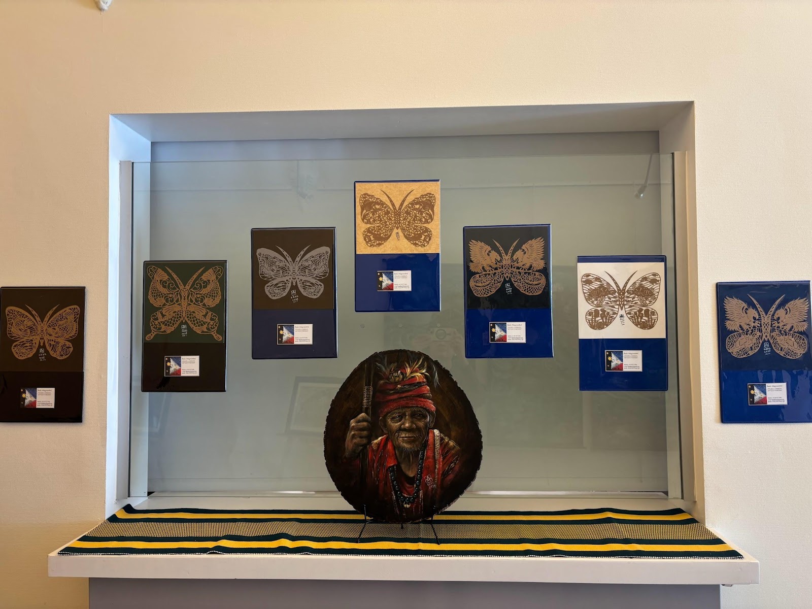 A display case with butterflies and a picture of a personAI-generated content may be incorrect.