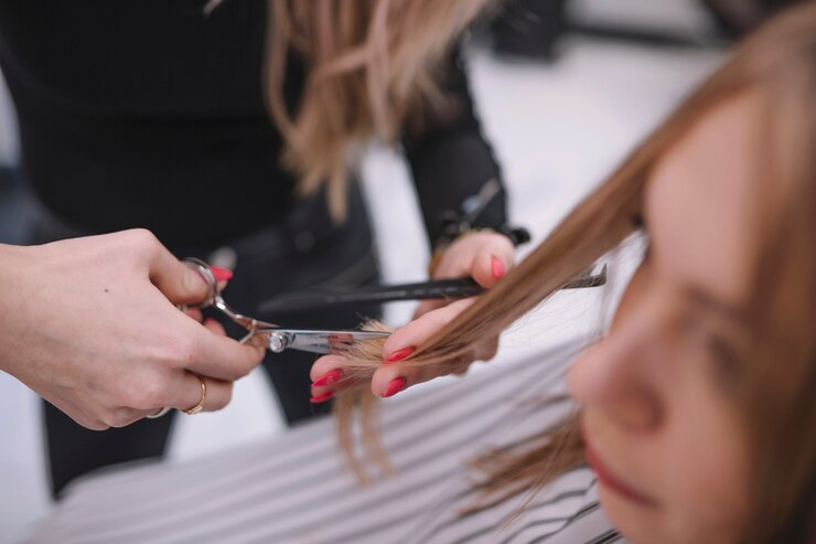 stylist trimming hair split ends of a customer