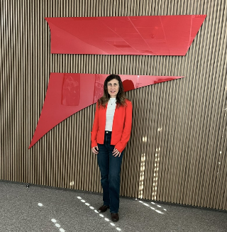 A person standing in front of a wall with red signs  Description automatically generated