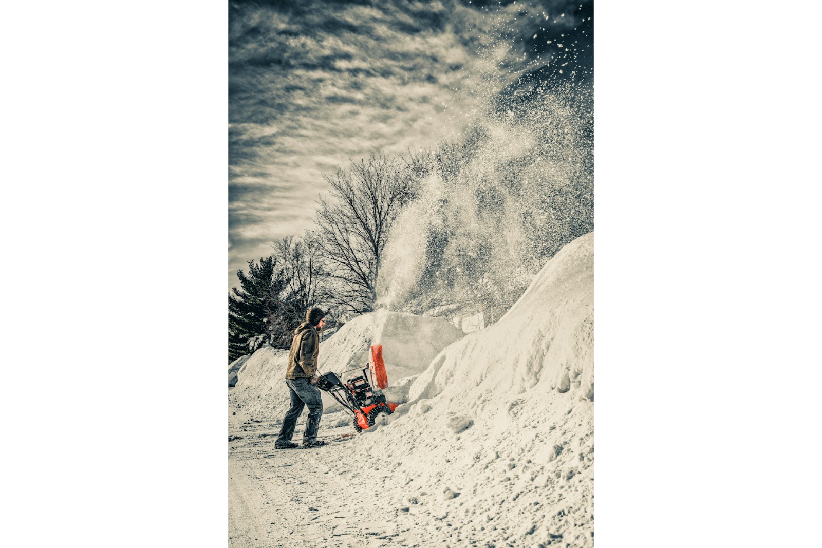 A man using a snow shovel with a blower.