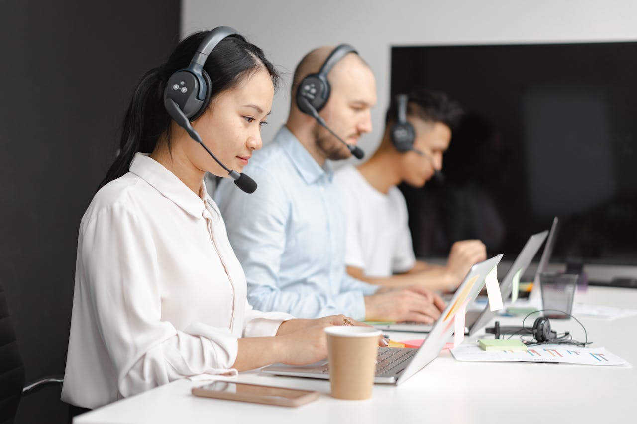 A team of customer support representatives wearing headsets and working on laptops, focused on providing assistance in a call center environment.